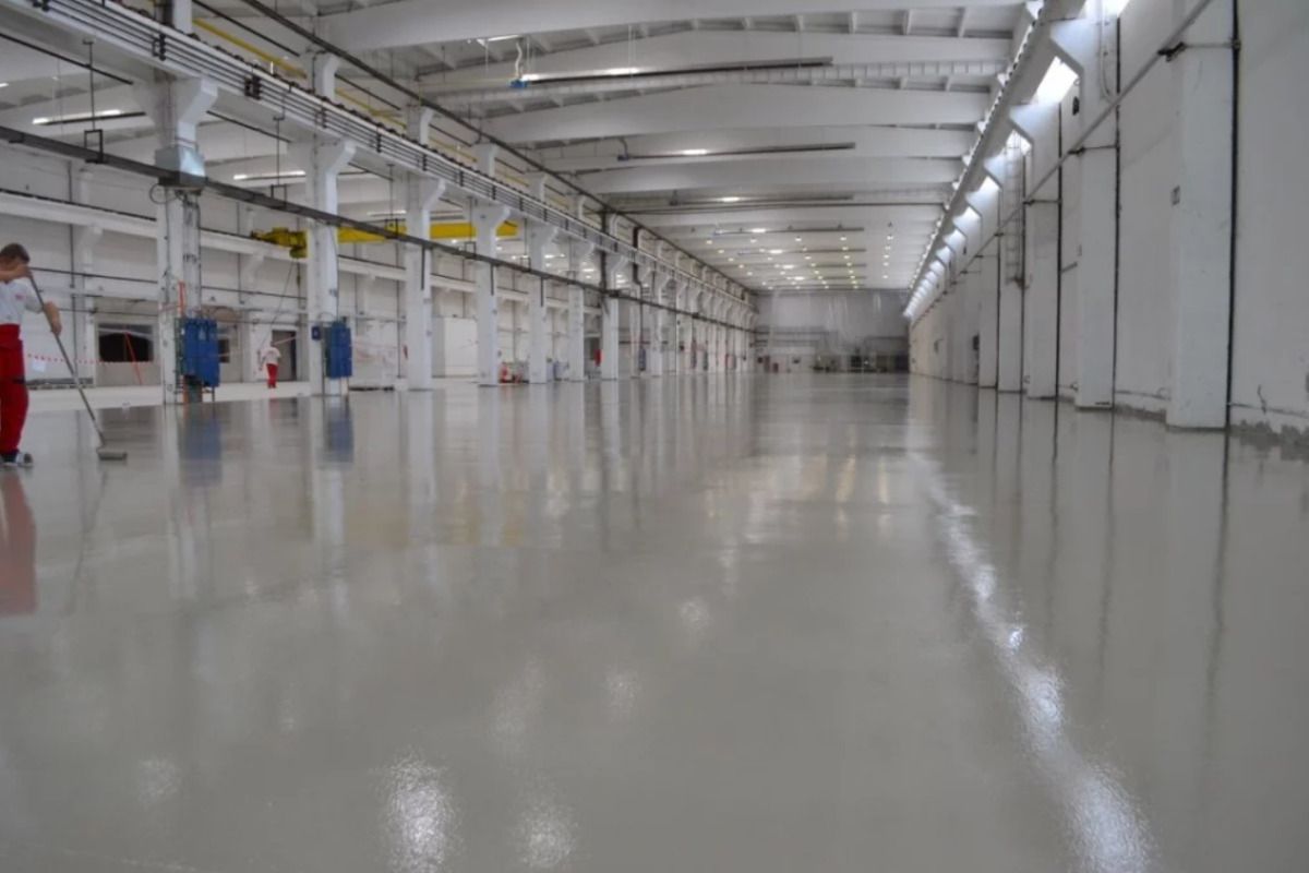 Profesionist care aplica pardoseala poliuretanica in spatiu industrial