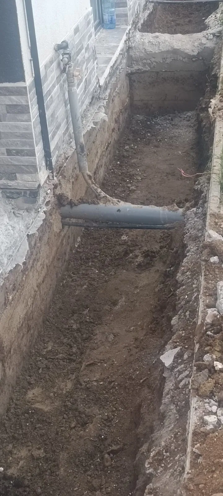Șanț perimetral excavat de-a lungul fundației, pregătit pentru hidroizolare