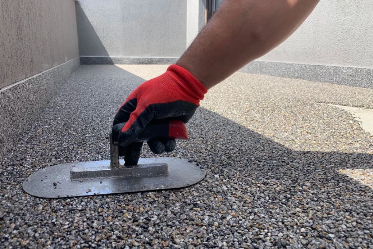 barbat care realizeaza finisajul balconului cu covor din piatra naturala