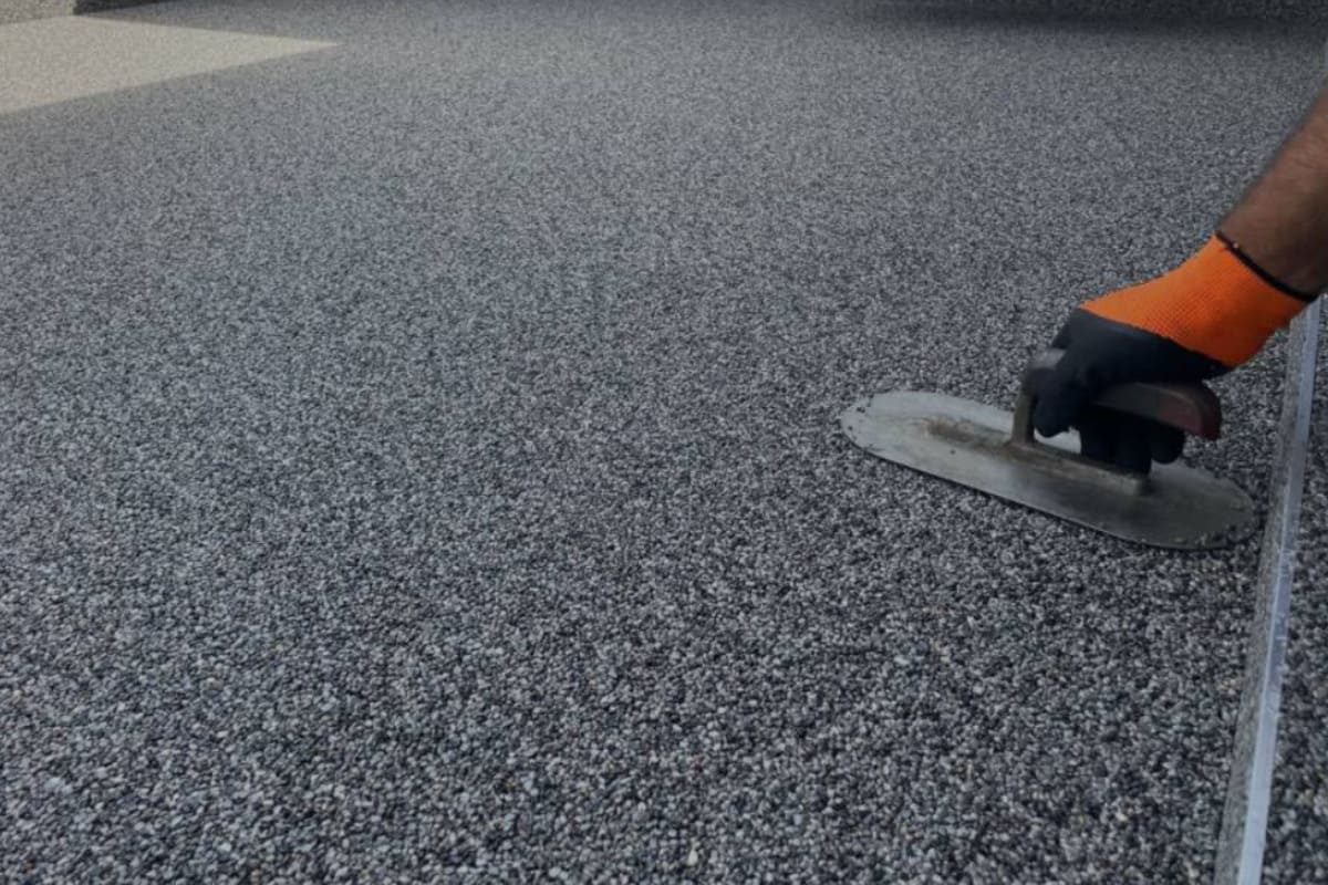 muncitor care niveleaza covorul de piatra naturala pe terasa