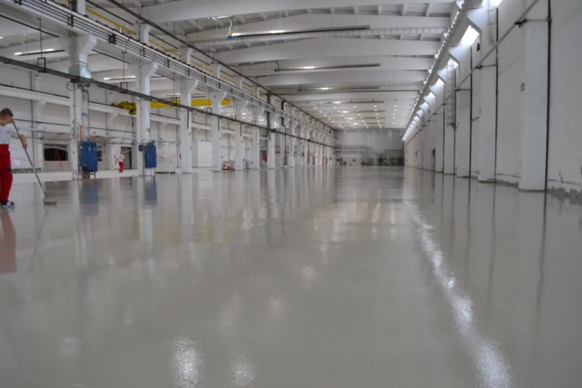 Profesionist care aplica pardoseala poliuretanica in spatiu industrial