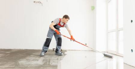 barbat care aplica pardoseala epoxidica intr-o locuinta moderna